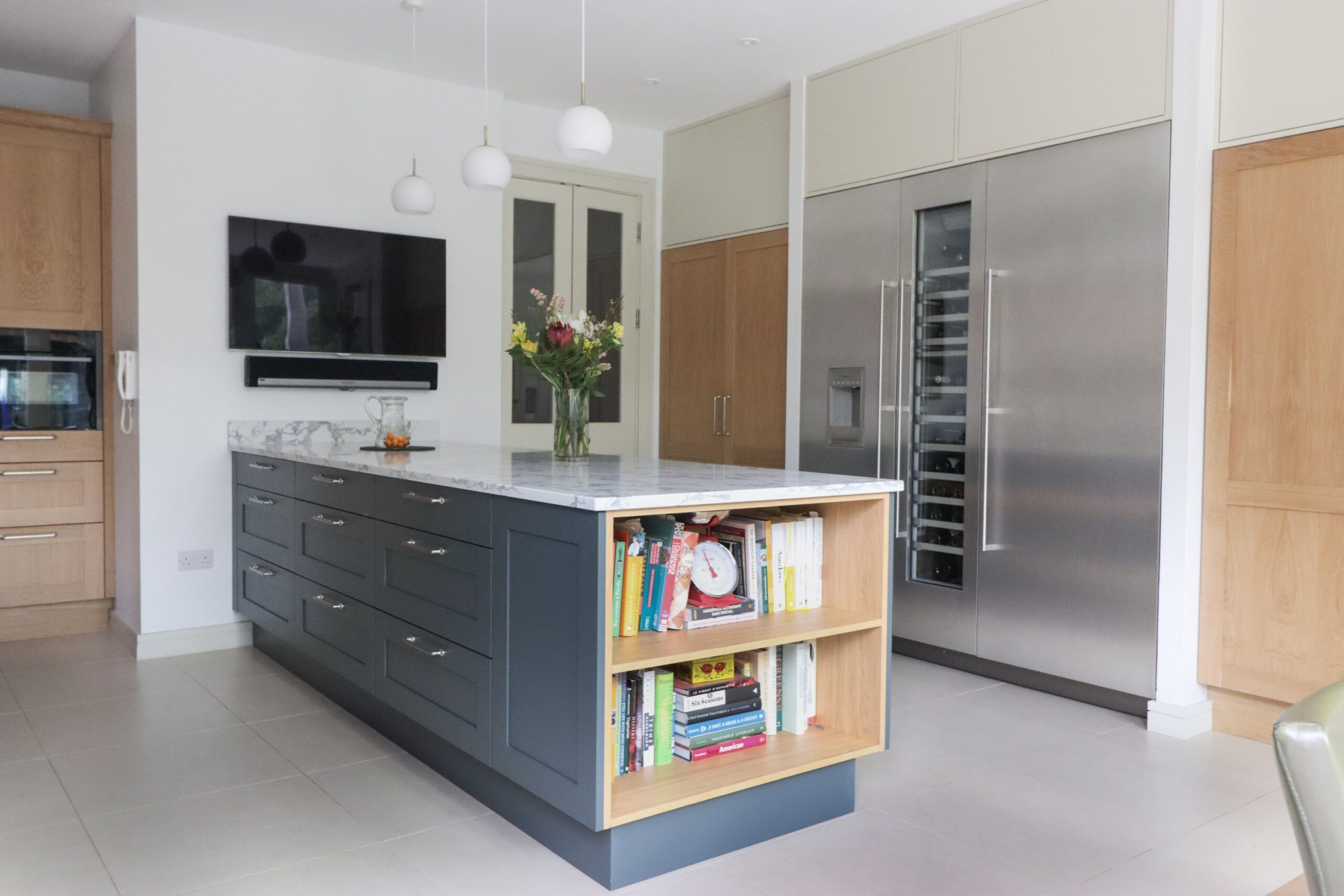 Shaker kitchen island with pendant lighting, built-in shelving and integrated appliances